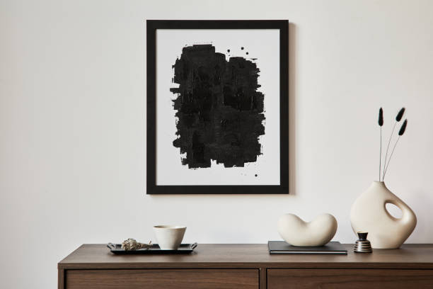 istock Minimalistic composition of creative living room interior with mock up poster frame and stylish small personal accessories on wooden commode. Copy space. Template. Real photo.