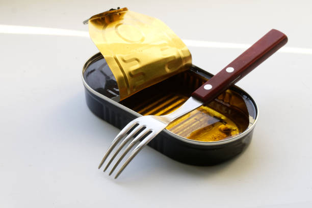 istock Fork and empty tin can with leftover oil on a white background. Leftover canned food with sprats. Eaten breakfast 1364398265