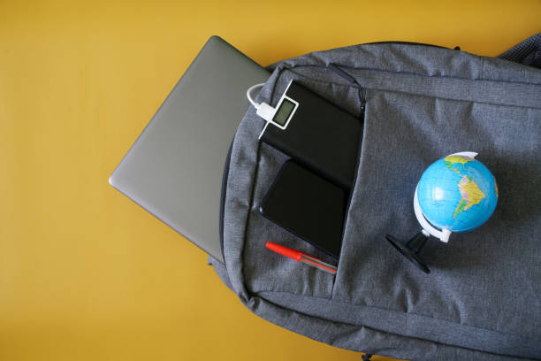 istock A smartphone, a thin laptop, an external battery - a power bank and a small globe in a fashionable textile backpack. Yellow background. The concept of the modern traveler's gadgets 1364398267