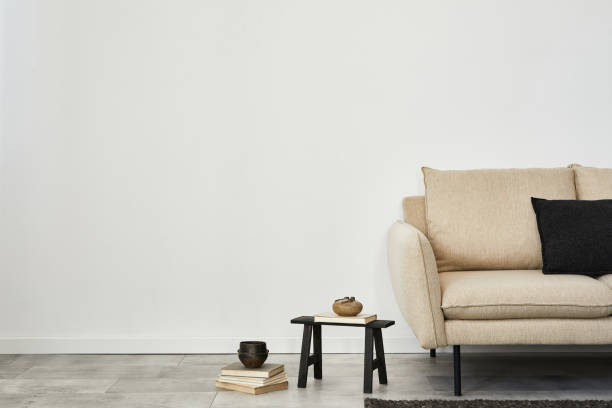 istock Minimalist living room interior design with beige sofa, small side table and modern home accessories. Wallpaper. Copy space. Template.  