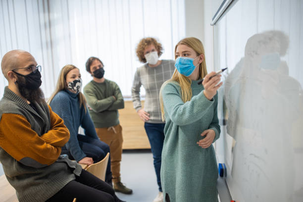istock Female professor explaining the lecture on whiteboard to a group of students 1364400544