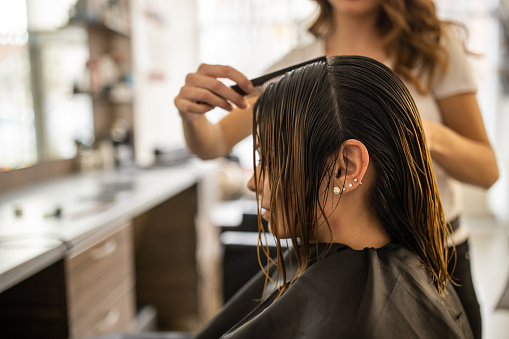 Professional female hairdresser, cutting her female client hair, at hair salon