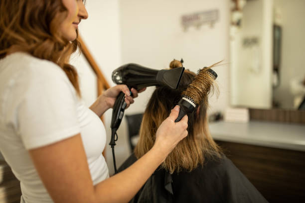 Skilled female hairdresser, with hair dryer drying, her female client hair Caucasian female hairdresser, with hair dryer drying, her female client hair, at the hair salon blow drying stock pictures, royalty-free photos & images