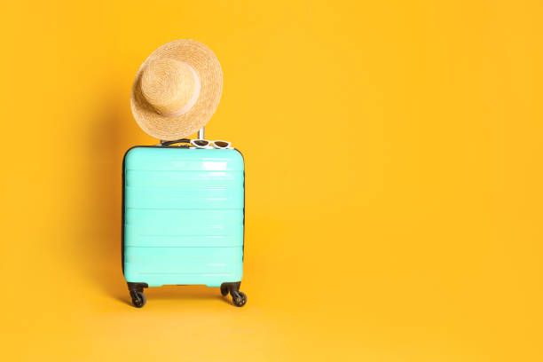 istock Travel suitcase with hat and sunglasses on yellow background, space for text. Summer vacation 1364402005