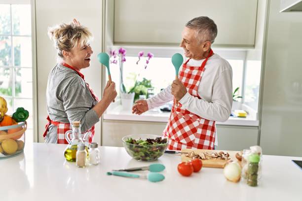 istock Senior caucasian couple smiling happy cooking at the kitchen. Singing using spoon as a microphone. 1364402832