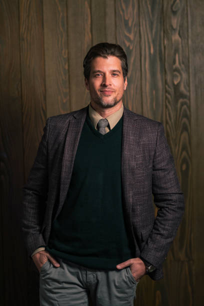 Formally dressed handsome male standing in front of a camera, being confident about his appearance.