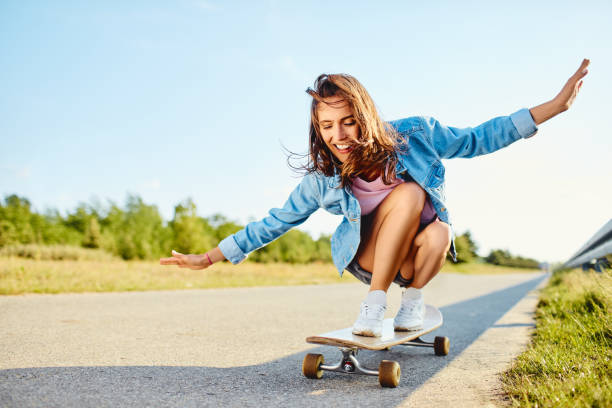 istock Happy young woman riding longboard during sunny summer day 1364408829