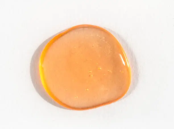 Photo of Orange cosmetics gel or slime drop on white background