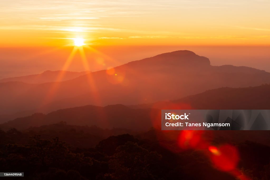 The sun rising over mountains on a winter day. The glowing sun rising over mountains range on a cold winter day, the landscape of mountains on the morning mist. Inspiration, positive thinking concepts. Soft focus. Sunrise - Dawn Stock Photo