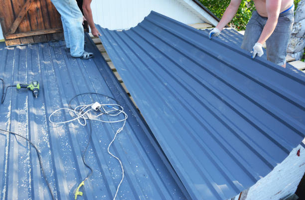 istock Metal roofing construction. Two building contractors are laying down and installing large metal roofing sheets onto the roof sheathing. 1364409594