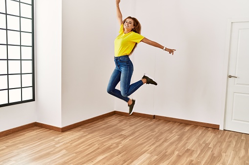 Young woman smiling confident jumping at empty room