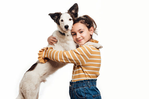 A young girl looking at the camera with her mongrel dog. Love between owner and dog. Isolated on white background. Studio portrait. Horizontal photography