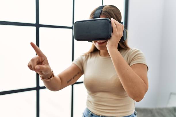 istock Young hispanic woman playing video game using virtual reality glasses at home 1364411222