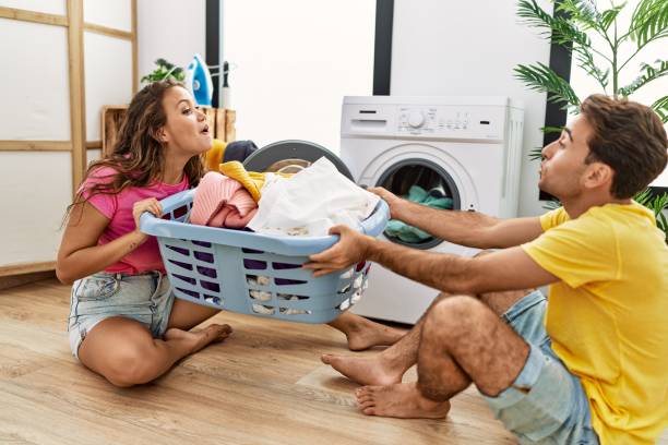 istock Man and woman couple pulling laundry basket at laundry room 1364412271