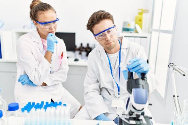 istock Man and woman wearing scientist uniform looking sample at laboratory 1364412293
