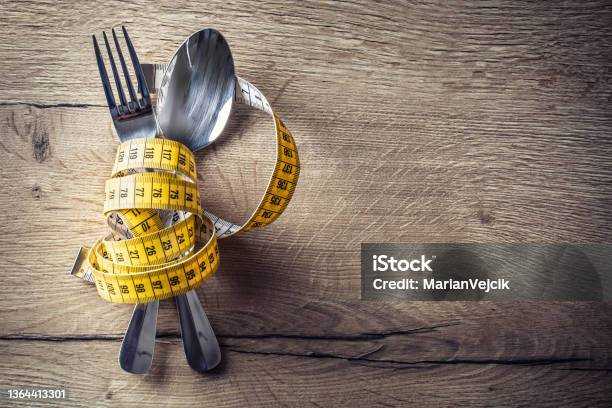 Spoon Fork And Measuring Tape On The Kitchen Table The Concept Of A Healthy Diet Stock Photo - Download Image Now