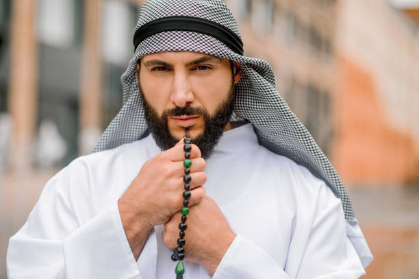 istock Bearded arabian guy in traditional headwear reading prayers 1364413765