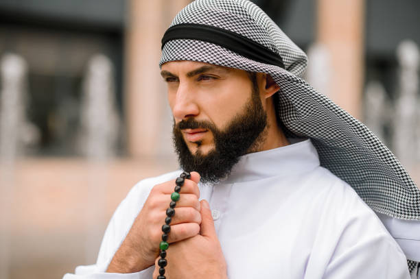istock Bearded arabian guy in traditional headwear reading prayers 1364413768