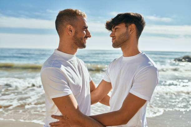 istock Romantic young gay couple at the beach. 1364414143