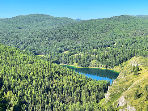Aerial view of mountain lake with turquoise water surrounded by dense forest, Altai, Russia