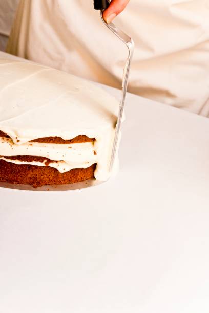 istock Confectioner spreading cream around a gateau 1364416683