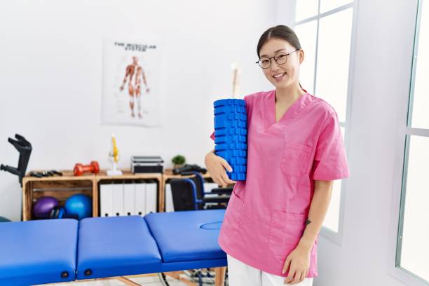 Young asian woman holding rehabilitation roller at physiotherapy clinic stock photo