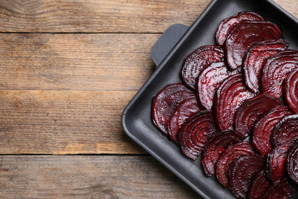 istock Baking dish with roasted beetroot slices on wooden table, top view. Space for text 1364417630