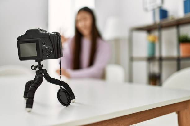 istock Young chinese girl having video call using camera sitting on the table at home. 1364417755