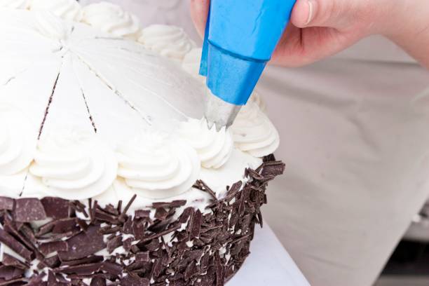 istock Decorating a gateau with whipped cream swirls 1364421796