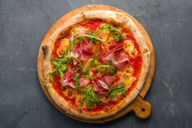 istock Pizza with Parma ham and arugula on the board on grey concrete table top view 1364421824