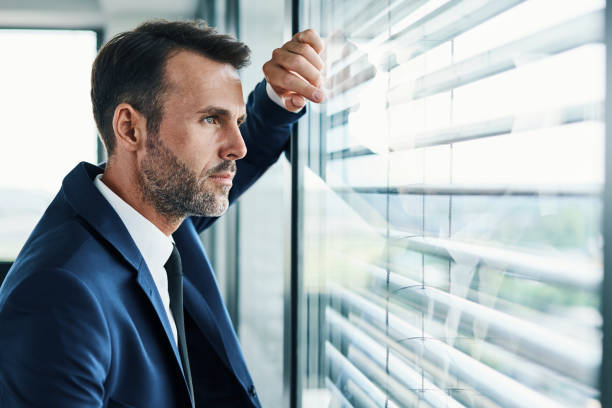 istock Thoughtful businessman looking through office window 1364422292