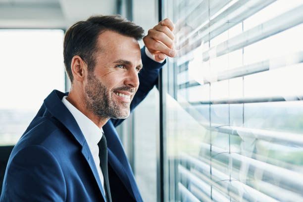 istock Successful businessman looking outside office window 1364422308