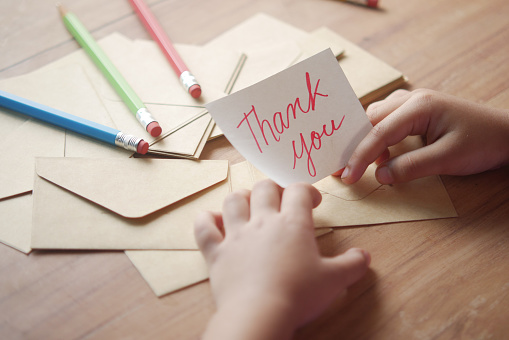 child hand holding thank you letter on table ,