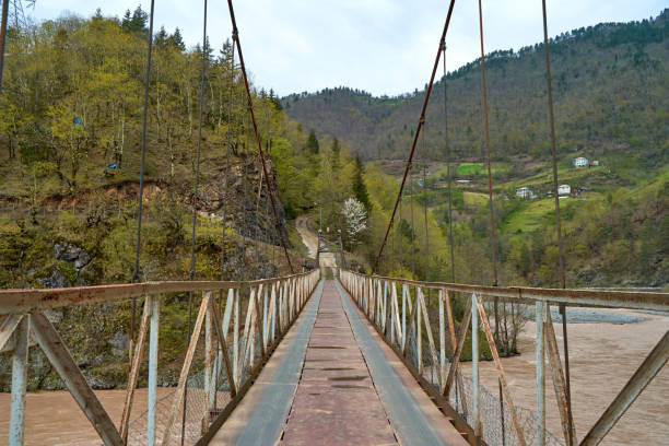 istock Wobbly old bridge over a mountain river for cars. 1364423972