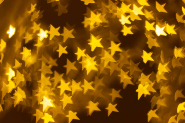 Blurred Golden stars bokeh background with copy space. Concept holidays of Christmas and Happy New Year. Festive abstract background