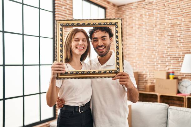 istock Young two people holding empty frame together smiling and laughing hard out loud because funny crazy joke. 1364424880