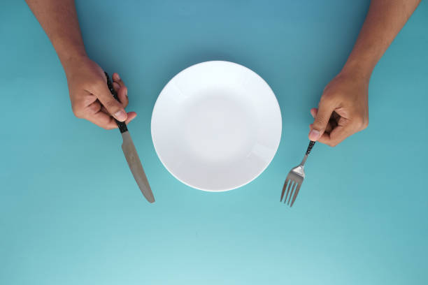 istock hand holding cutlery with empty plate on wooden table 1364425105