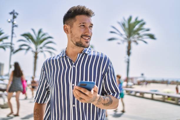 istock Young handsome man using smartphone by the sea 1364425588