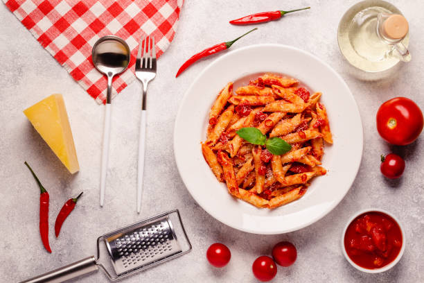 Classic italian pasta penne alla arrabiata with fresh basil on a light background, top view stock photo