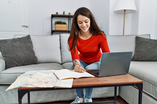 Young hispanic woman smiling confident organizing trip at home