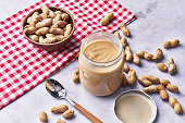 Bowl of peanuts with shell and peanut butter cream on a marble surface