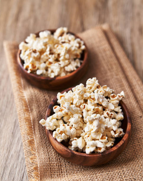 Bowls of salty popcorns on a wooden surface stock photo