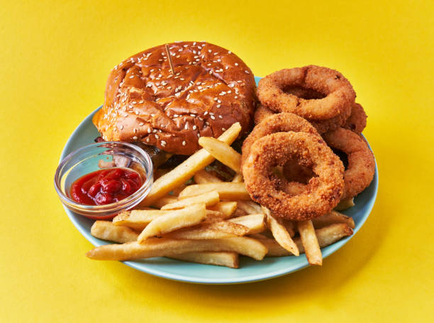 istock Plate of classical hamburger with chips potatoes and onion rings on a yellow background 1364431402