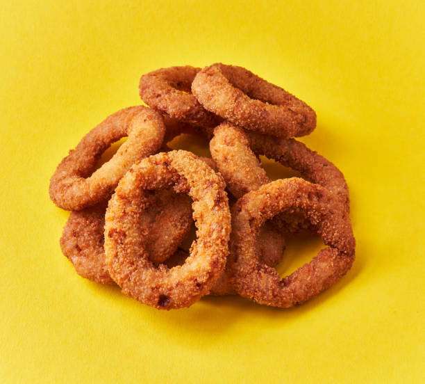 istock Bunch of breaded onion rings on a yellow background 1364431410