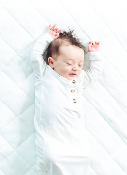 istock Cute gender neutral newborn baby stretching and sleeping on white background 1364433497