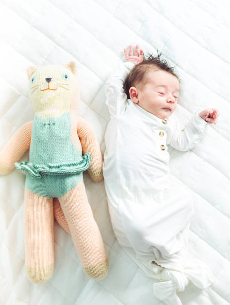 istock Small newborn baby stretching and sleeping on white background with toy 1364433707