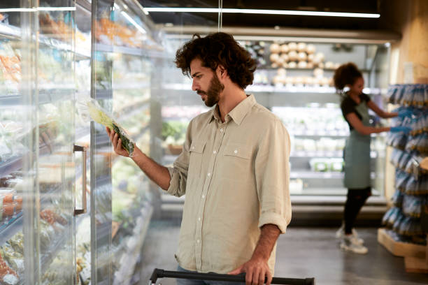 男はスーパーマーケットの冷蔵庫で製品を選択しています。 - convenience store merchandise consumerism customer ストックフォトと画像