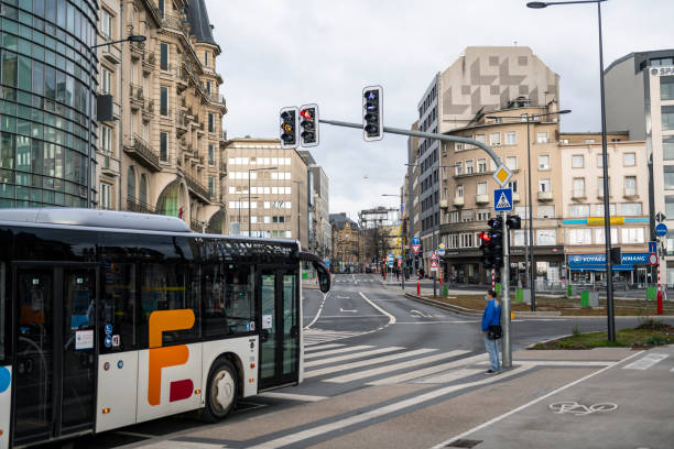 Luxembourg, Luxembourg - November 22, 2021: A pedestrian wearing a face mask waits to cross the street outside the train station in Luxembourg City.