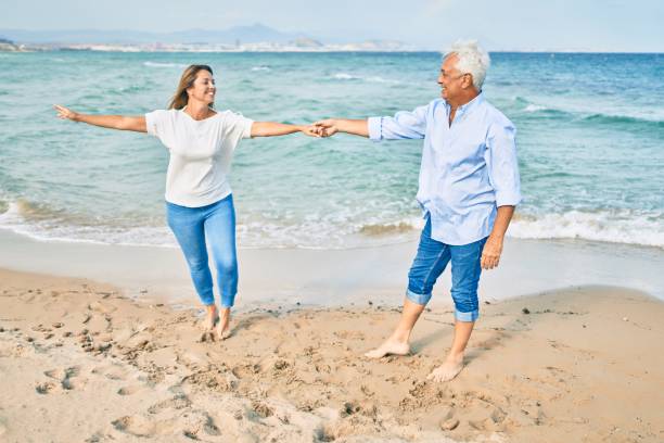 一緒に幸せで陽気なビーチで踊る愛の中年のカップル - senior adult retirement mature adult couple ストックフォトと画像