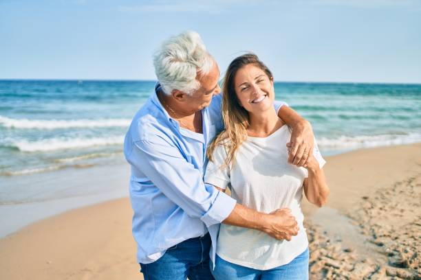 istock Middle age hispanic couple smiling happy and hugging walking at the beach 1364436447